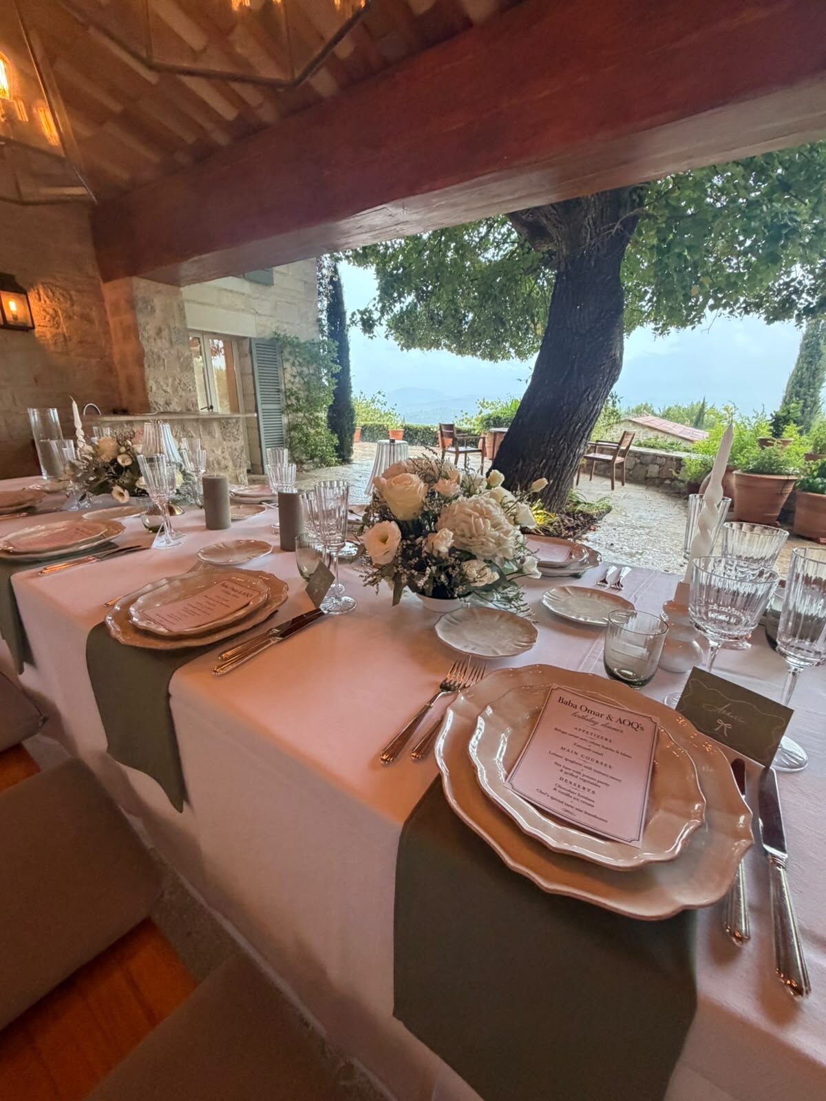 Private dining table set under a stone loggia with a view over the hills