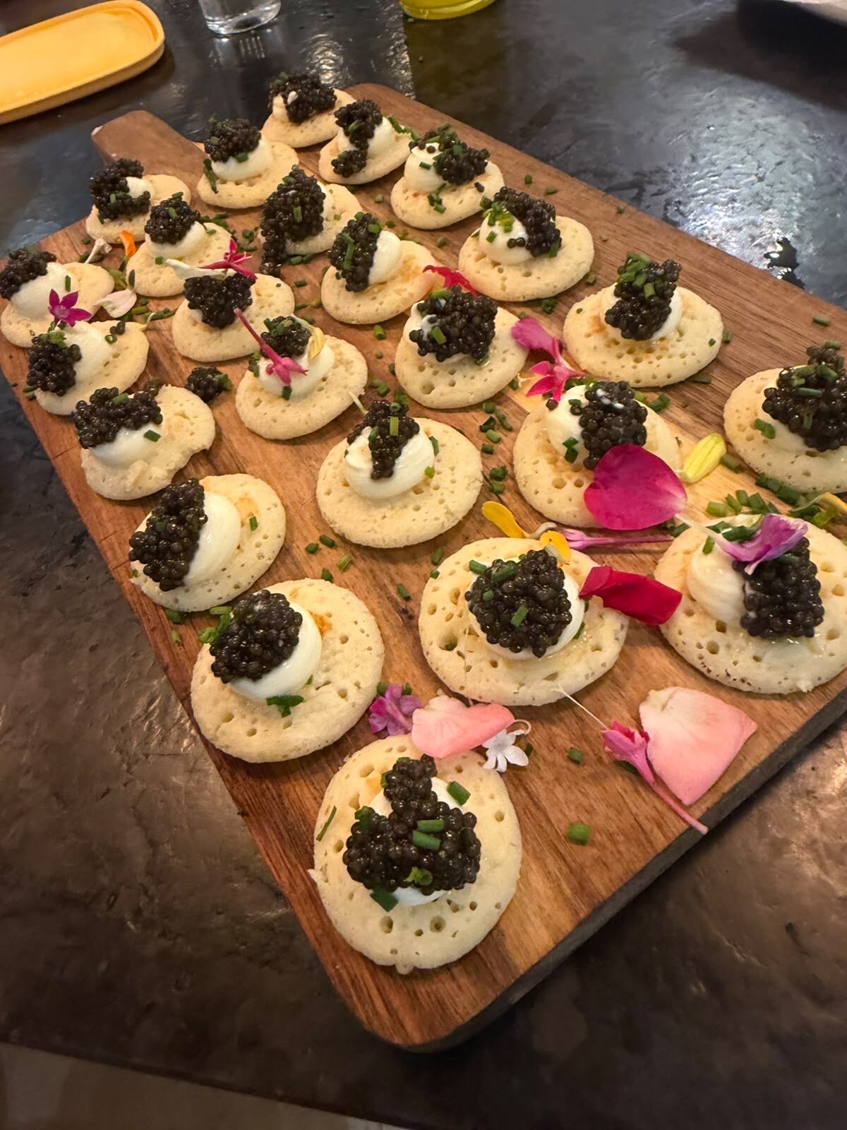Blinis with crème fraîche and caviar arranged on a wooden board
